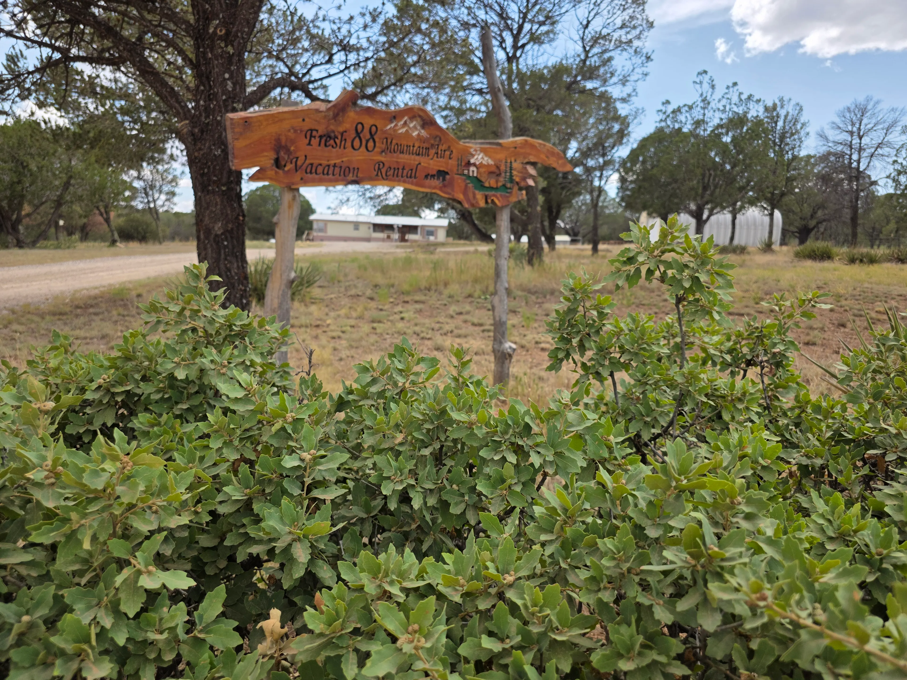 Carved wood entrance sign, house behind